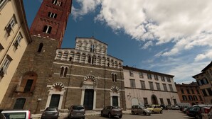 Un bâtiment historique doté d’un imposant clocher et de fenêtres en arc de cercle, entouré de voitures garées.