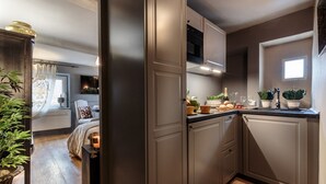 Une cuisine moderne avec des meubles de rangement sombres, un four encastré et une fenêtre.