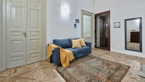 Una habitación con un sofá azul, un tapete estampado y un espejo grande.