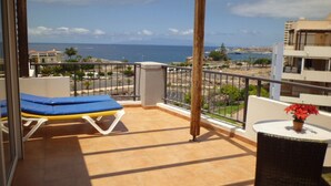 A balcony with a view of the sea, a sun lounger, and a small table with a potted plant. - El Rincon 3 (Los Cristianos)