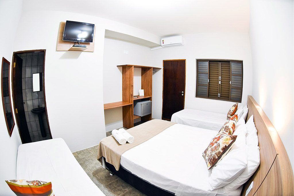 A hotel room with two beds, a TV, a wardrobe, and a desk.
