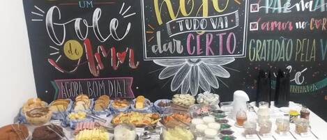 A buffet table with various food items and a chalkboard with inspirational messages.