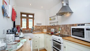 Eine moderne Küche mit weißen Schränken, einer Edelstahl-Dunstabzugshaube, einer Mikrowelle und einem Toaster.