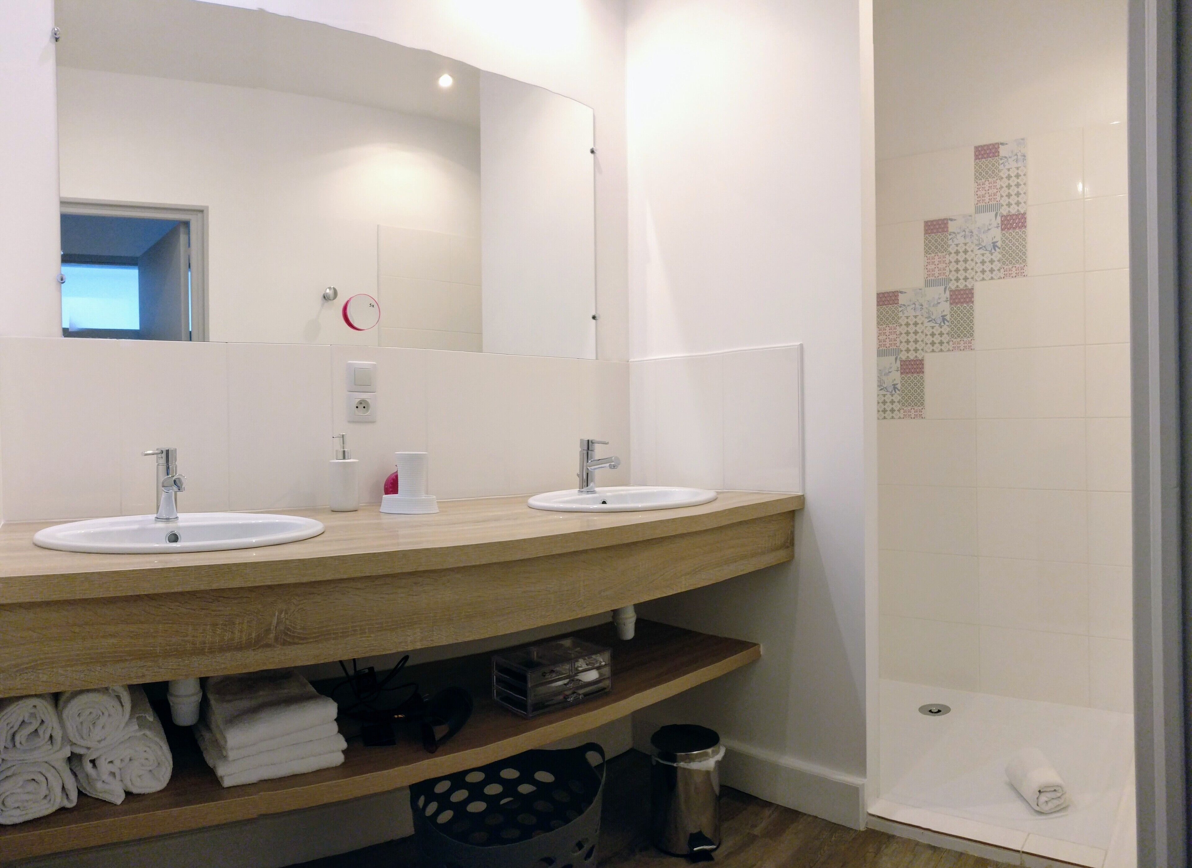 A bathroom with two sinks, a mirror, and a shower area.