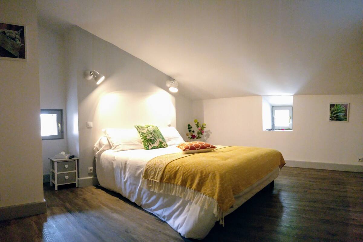 A bedroom with a bed, bedside tables, a window, and a small nightstand.