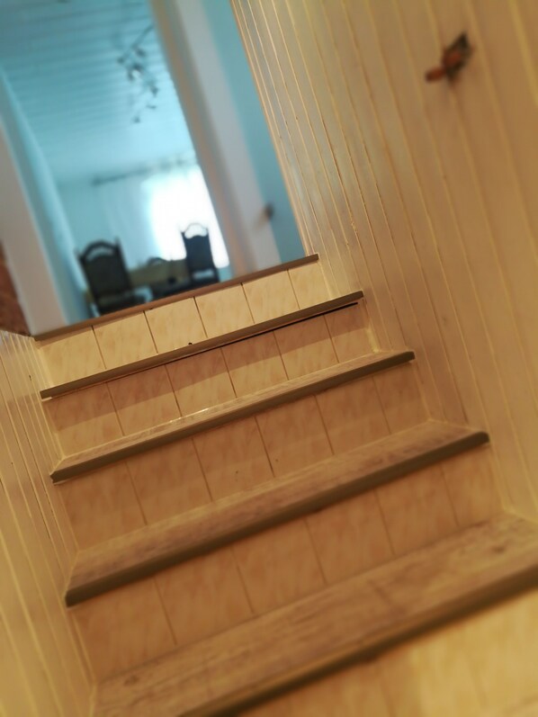 Una escalera de madera con barandilla y una puerta al final.