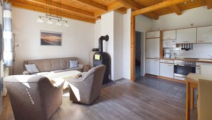 A cozy living area with a sofa, chairs, a table, and a wood-burning stove. - Family-friendly terraced house with fireplace, WiFi, sauna, pets allowed (Ostseebad Prerow)