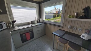 A modern kitchen with a built-in oven, a sink, and a window overlooking a garden. - Holiday home "Zur Lehns" with garden (Darlingerode)