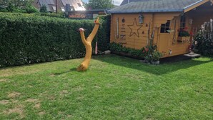 A wooden playhouse with a star decoration, surrounded by a well-maintained lawn and a hedge. - Holiday home "Zur Lehns" with garden (Darlingerode)
