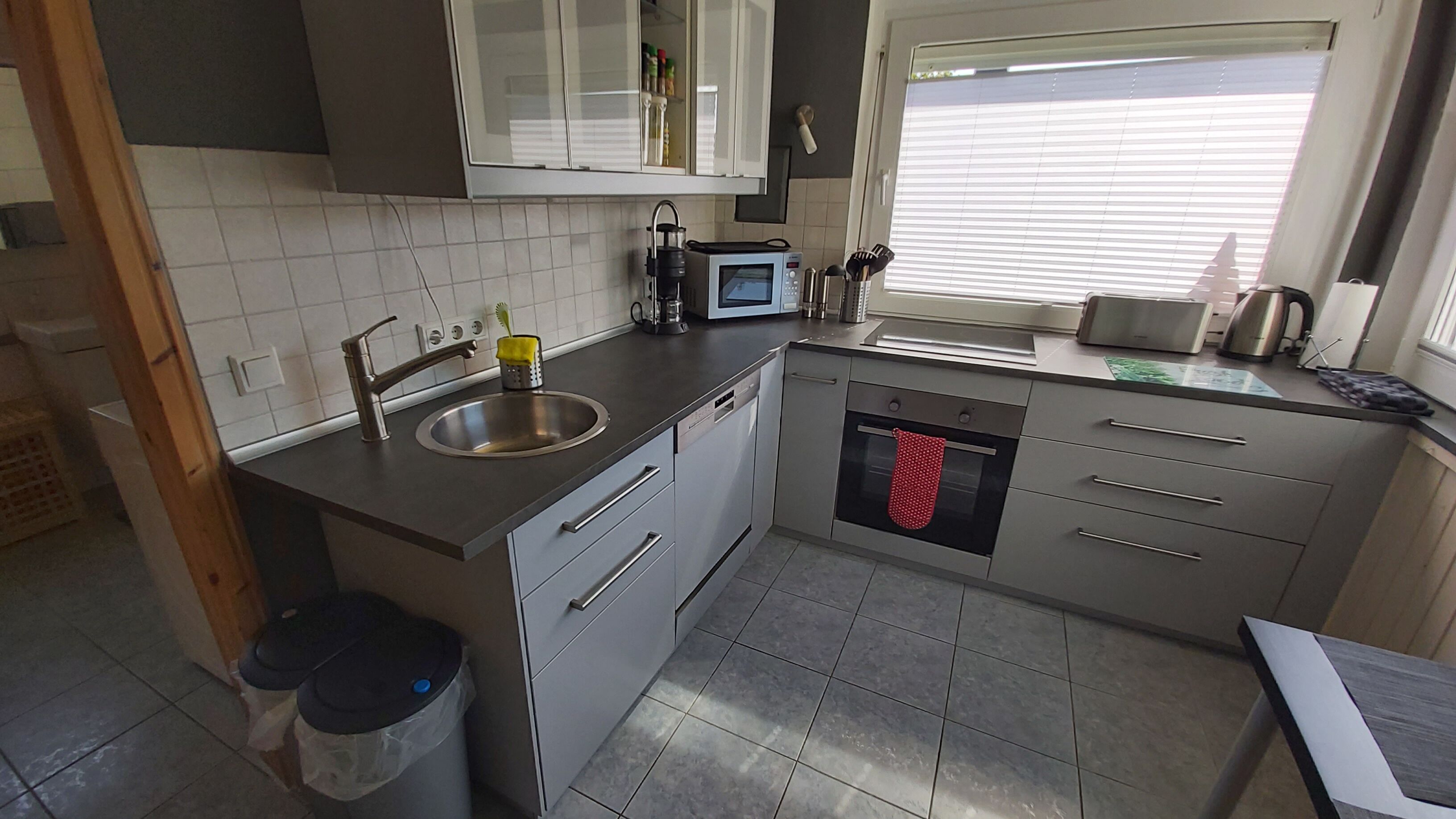 A modern kitchen with a sink, microwave, oven, and stainless steel cabinets.