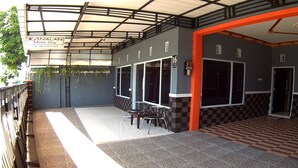 A covered outdoor area with a checkered floor, a sheltered seating area with tables and chairs, and a sign for 'KANALAN Home Stay'. - Kanalan Homestay (Banyuwangi)