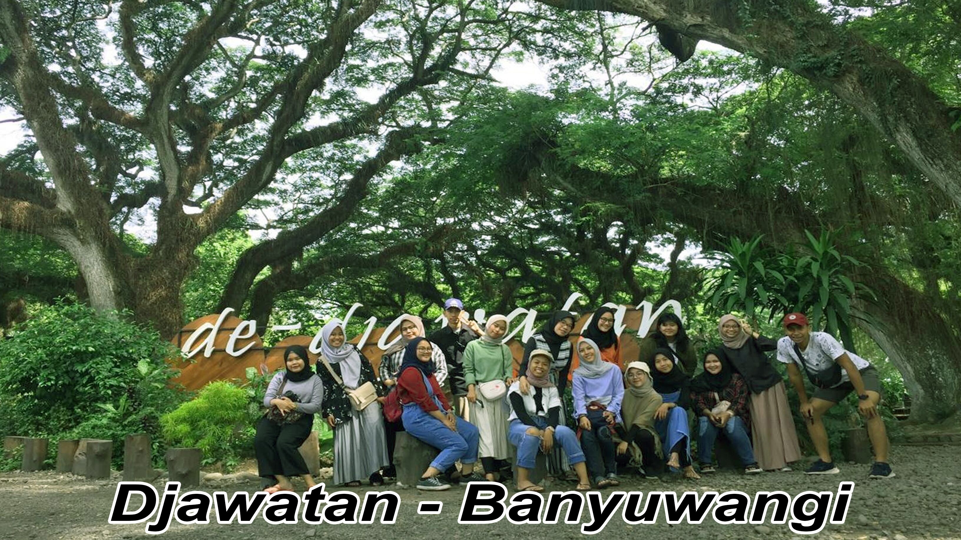 A group of people posing under a large tree in a natural setting.