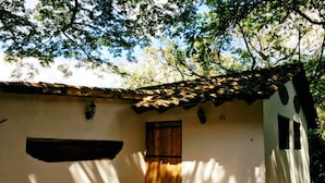A rustic building with a tiled roof, a wooden door, and a small window.