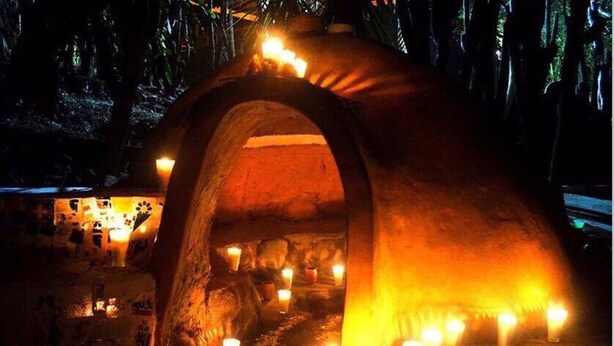 A cave-like structure with a warm, glowing interior, illuminated by multiple candles.