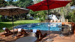 A pool area with lounge chairs, a table, and umbrellas.