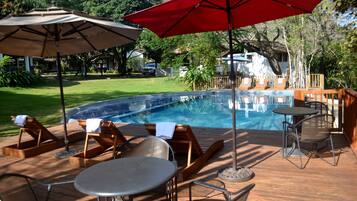 Alberca al aire libre, sombrillas en la alberca y camastros