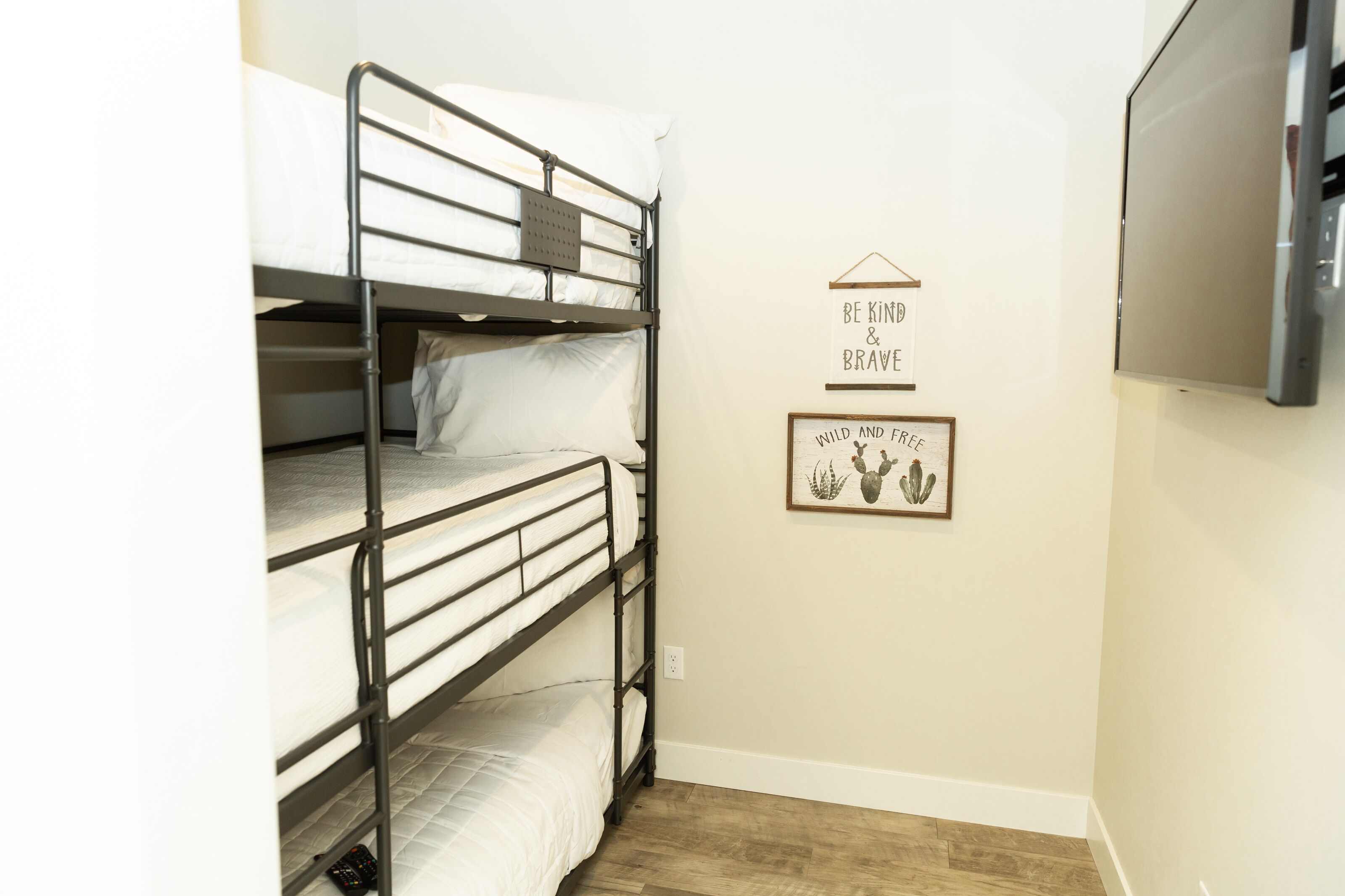 A bunk bed room with a motivational quote and a cactus picture on the wall.