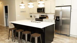 A modern kitchen with a central island, stainless steel appliances, and bar stools.