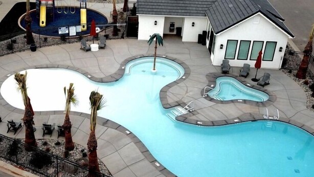 A swimming pool with a unique design, surrounded by lounge chairs and palm trees.