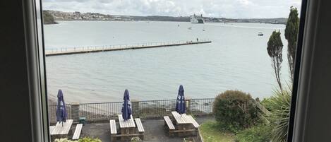 A view of a waterfront area with a pier, picnic tables, and umbrellas.