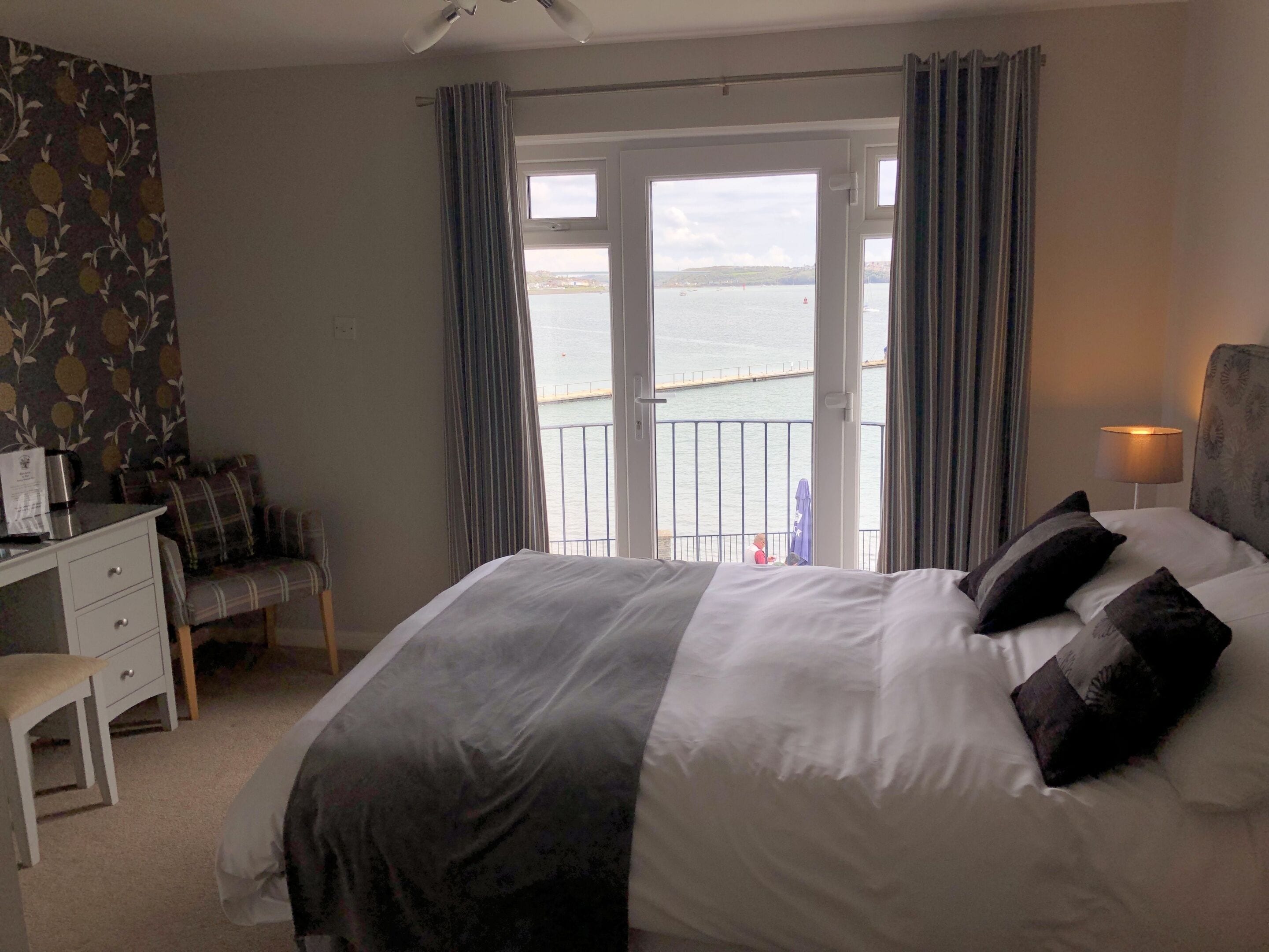 Ein Hotelzimmer mit Bett, Schreibtisch, Stuhl und Meerblick vom Balkon.