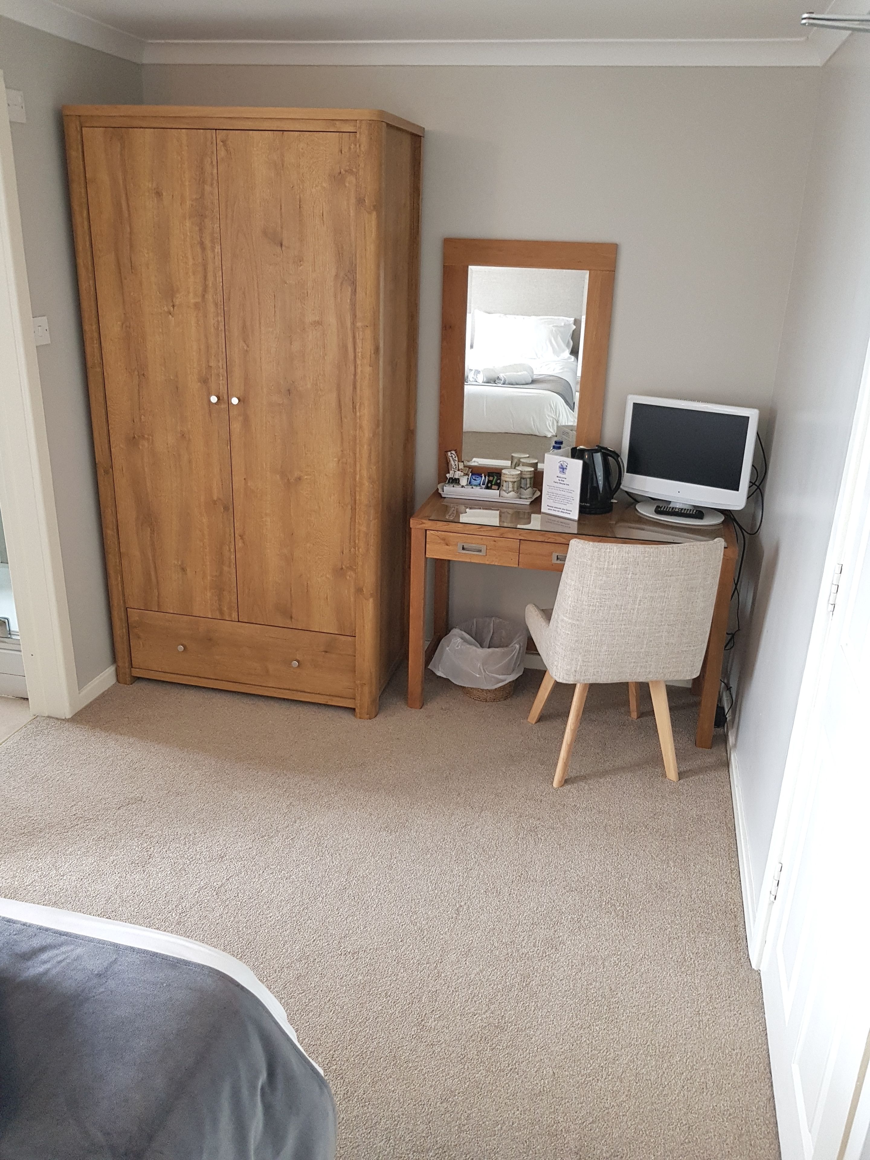 Un dormitorio con un armario de madera, un escritorio con computadora, una silla y una cama.