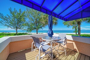 Une terrasse extérieure avec vue sur la plage, comprenant une table ronde et deux chaises.