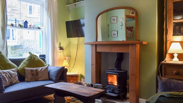 A cozy living room with a fireplace, a sofa, a coffee table, and a television. - 3 bedroom accommodation in Staithes, near Saltburn-by-the-Sea (Staithes, near Saltburn-by-the-Sea)