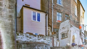 A narrow street with old buildings, a stone wall, and a staircase leading up to a door. - 3 bedroom accommodation in Staithes, near Saltburn-by-the-Sea (Staithes, near Saltburn-by-the-Sea)