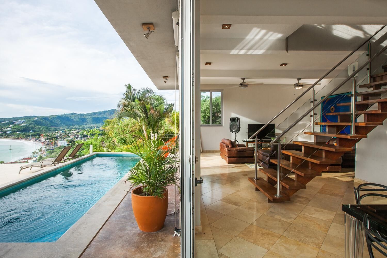 A modern interior with a pool, a staircase, and a view of the beach.