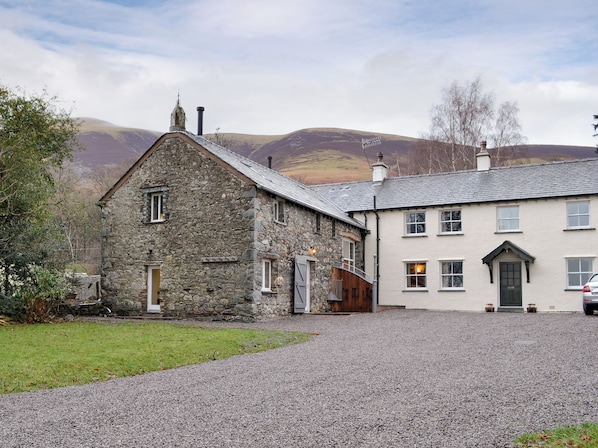 A stone building with a sloped roof and a white building with a door and windows.