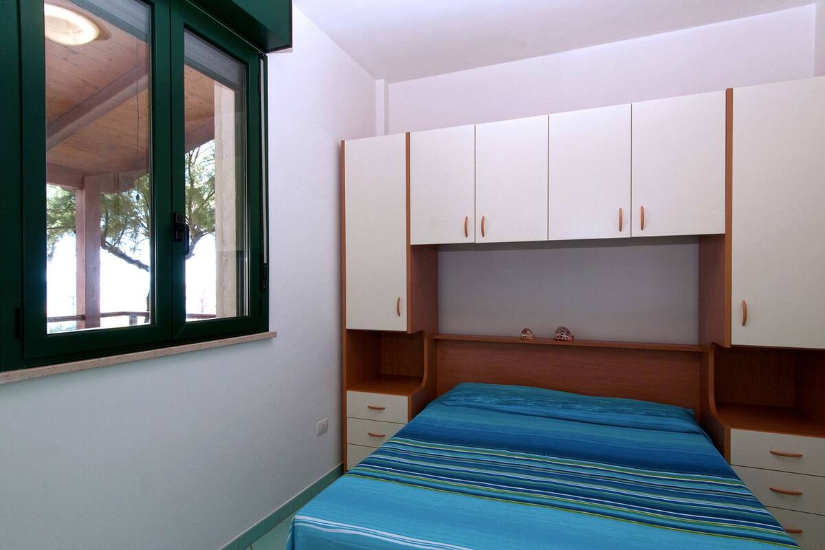 A bedroom with a bed, a window, and built-in cabinets.