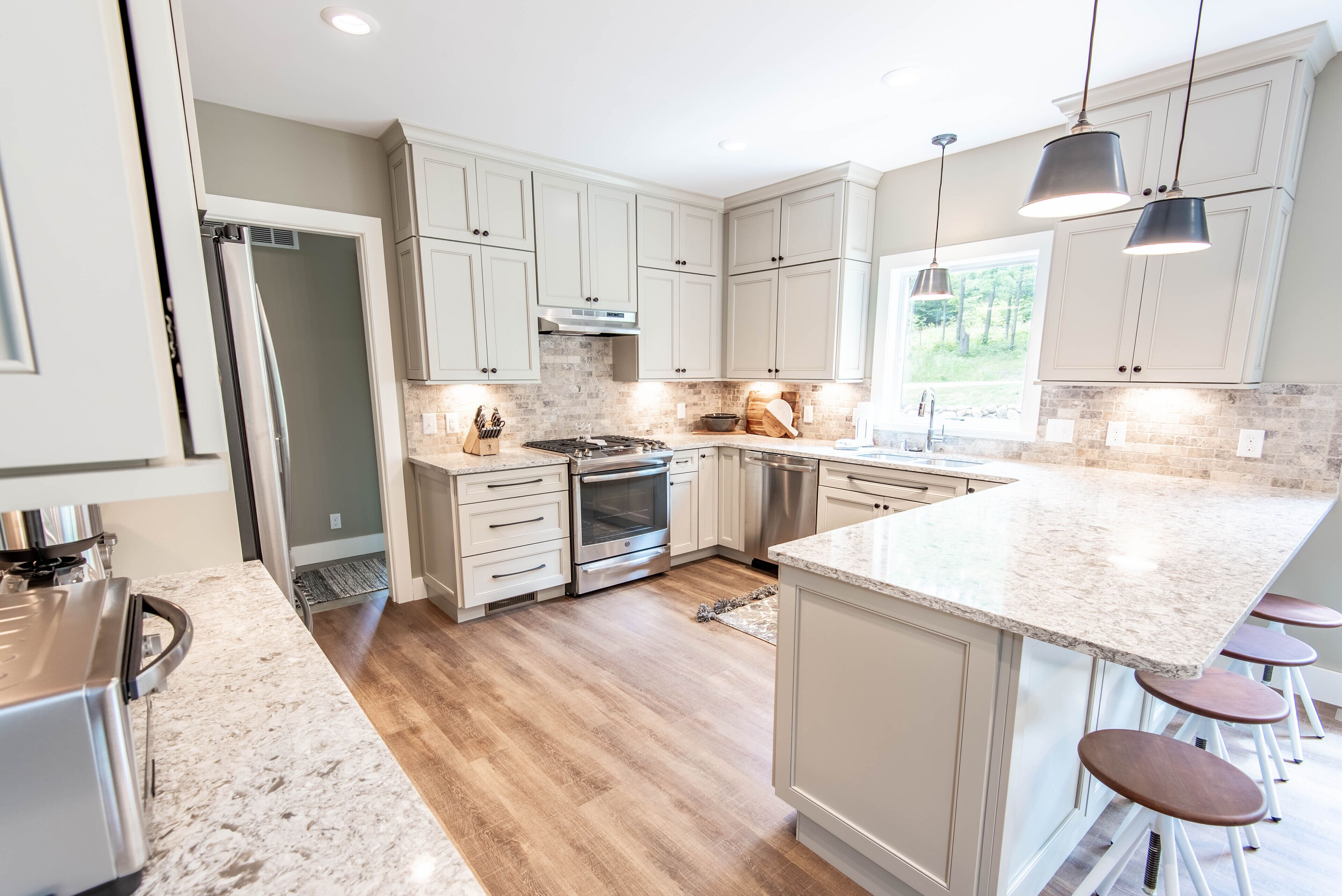 A modern kitchen with white cabinets, a granite countertop, and a built-in island with bar stools.