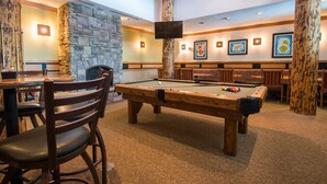 A pool table in a room with stone walls, wooden chairs, and a television mounted on a wooden pillar. - Great Value! Well-Equipped Condo in Crested Butte (Crested Butte)