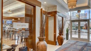 Hall d'albergo con un cartello che recita 'delights', una reception e vista sulla città attraverso ampie finestre.