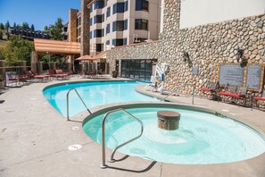 A pool area with lounge chairs and a stone wall. - Great Value! Cozy & Rustic Studio in Crested Butte (Crested Butte)