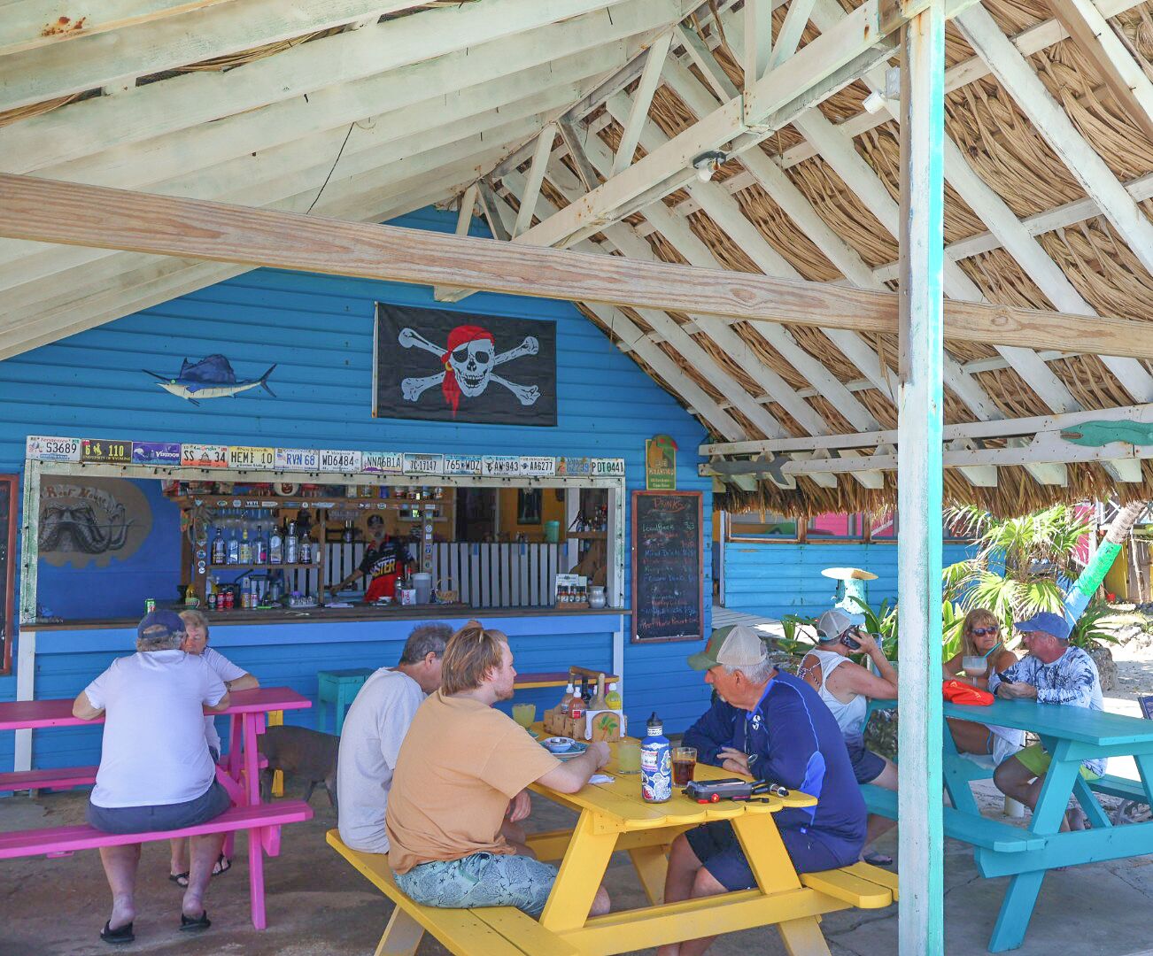 Un bar en la playa con terraza y techo de paja.