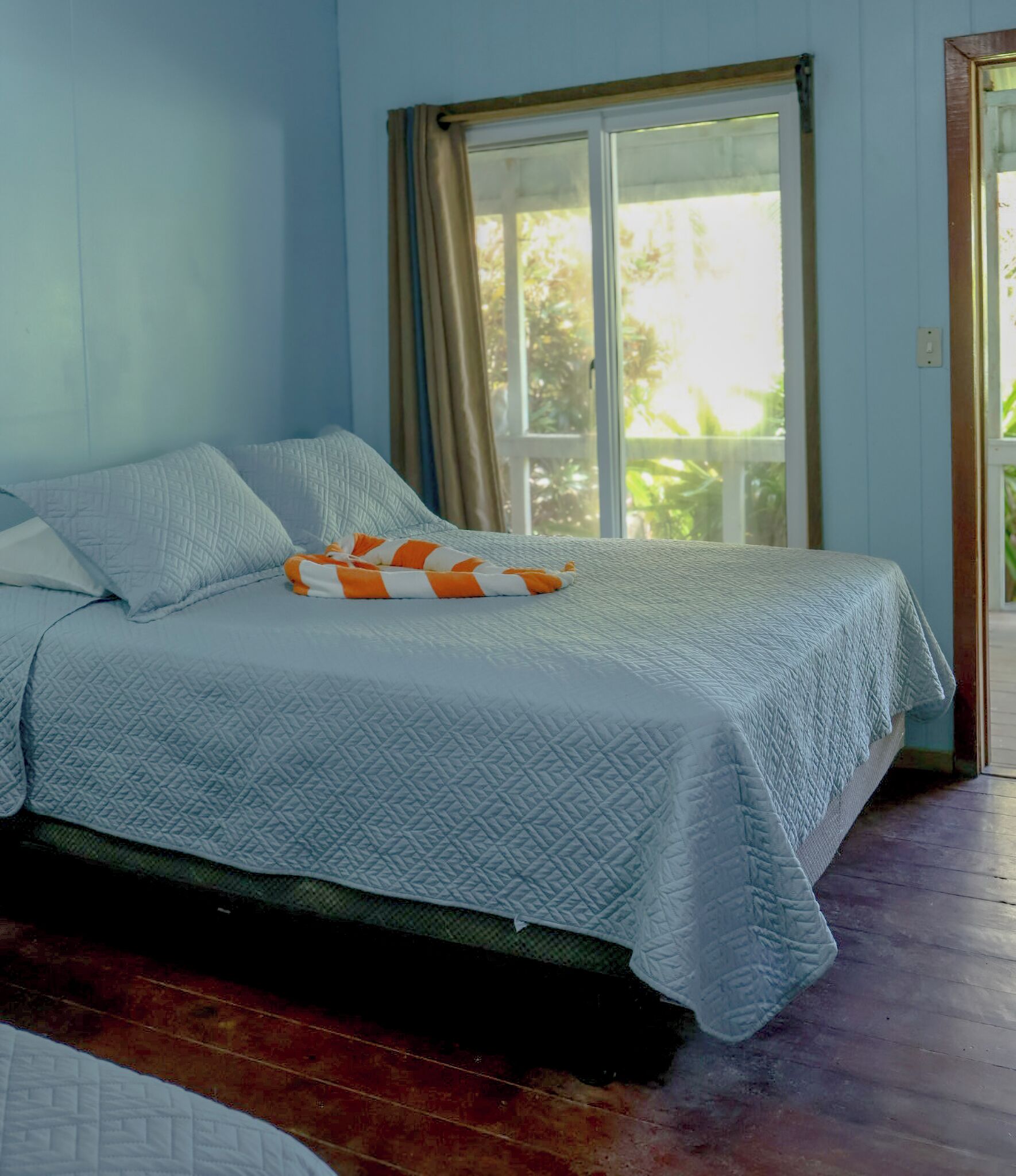 Un dormitorio con cama, ventana con cortinas y vistas al verde exterior.