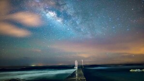 A pier extending into a body of water under a starry night sky. - Reef House (Roatan)