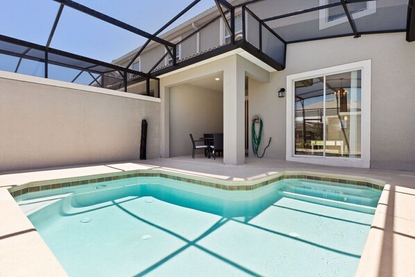 A swimming pool with a glass ceiling, a table and chairs, and a hose.