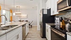 Una cocina moderna con encimeras de granito, electrodomésticos de acero inoxidable y salpicadero de azulejos.