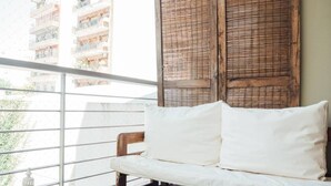 A balcony with a white sofa and wooden shutters.