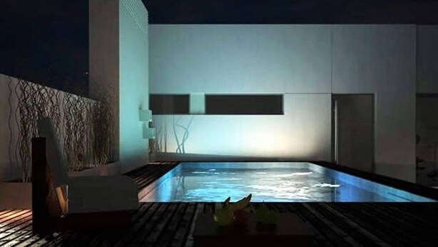 A modern building with a swimming pool at night, illuminated by artificial lighting.