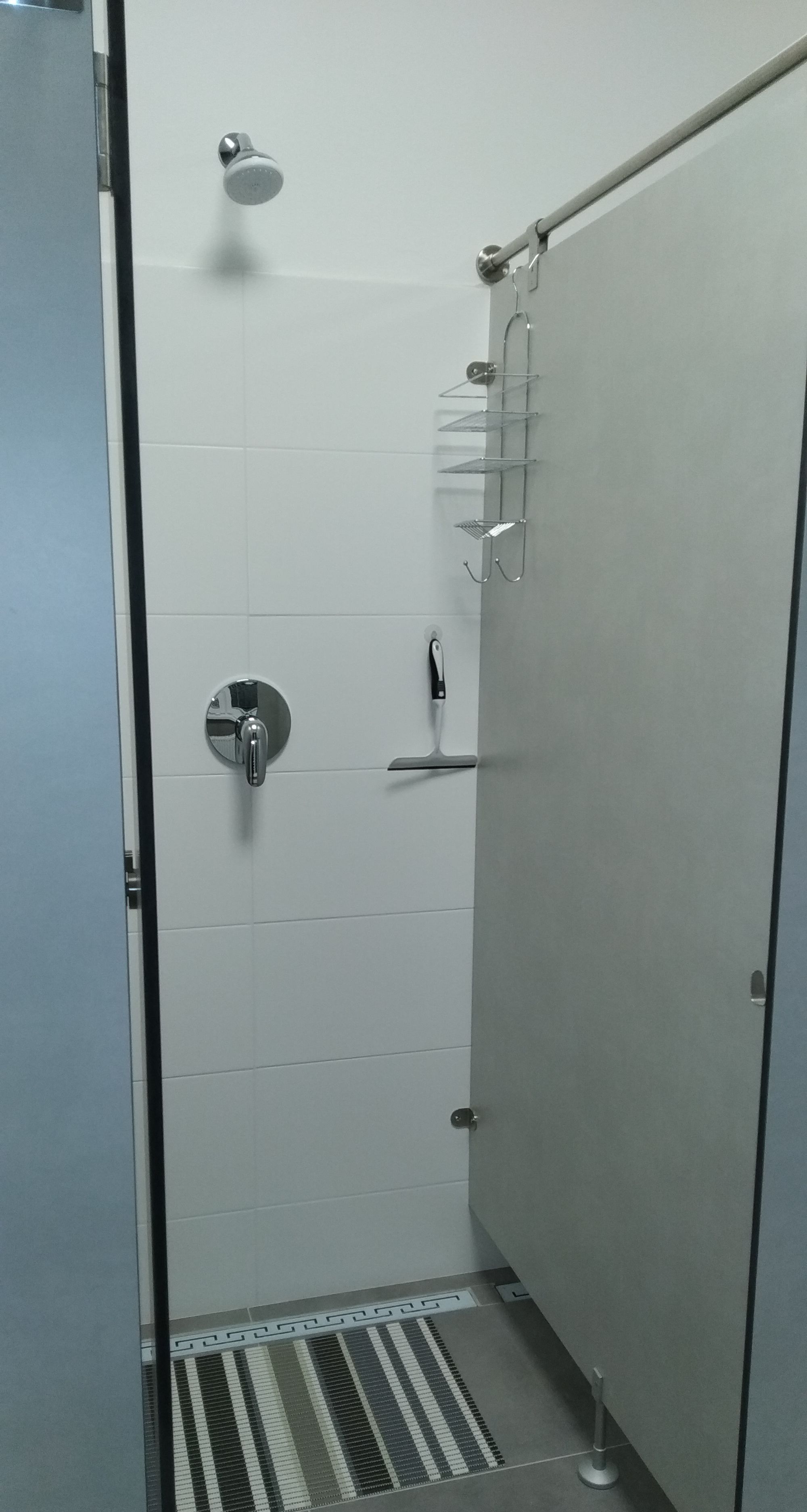 A small, enclosed shower area with a showerhead, a faucet, and a shelf for toiletries.