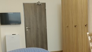 Una camera da letto con un letto, un armadio, una televisione e una piccola credenza bianca.