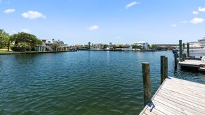 A marina with boats docked, a wooden dock, and buildings in the background. - Allendale Docks * Pet Friendly! Boat Dock on Holiday Isle * Salt Water Vacations (Destin)