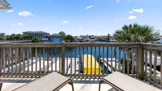 A wooden deck with a view of a marina and houses in the background. - Allendale Docks * Pet Friendly! Boat Dock on Holiday Isle * Salt Water Vacations (Destin)