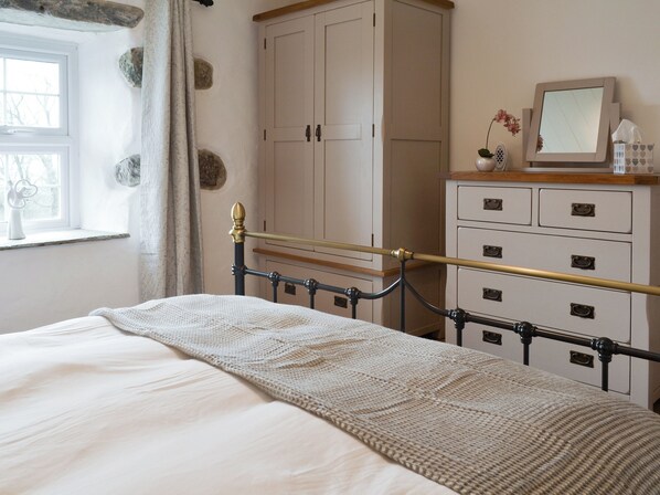 A bedroom with a bed, a dresser, a mirror, and a window with curtains.