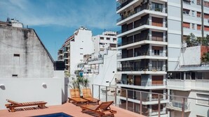 Un espace piscine sur le toit, avec des chaises longues et une petite piscine.