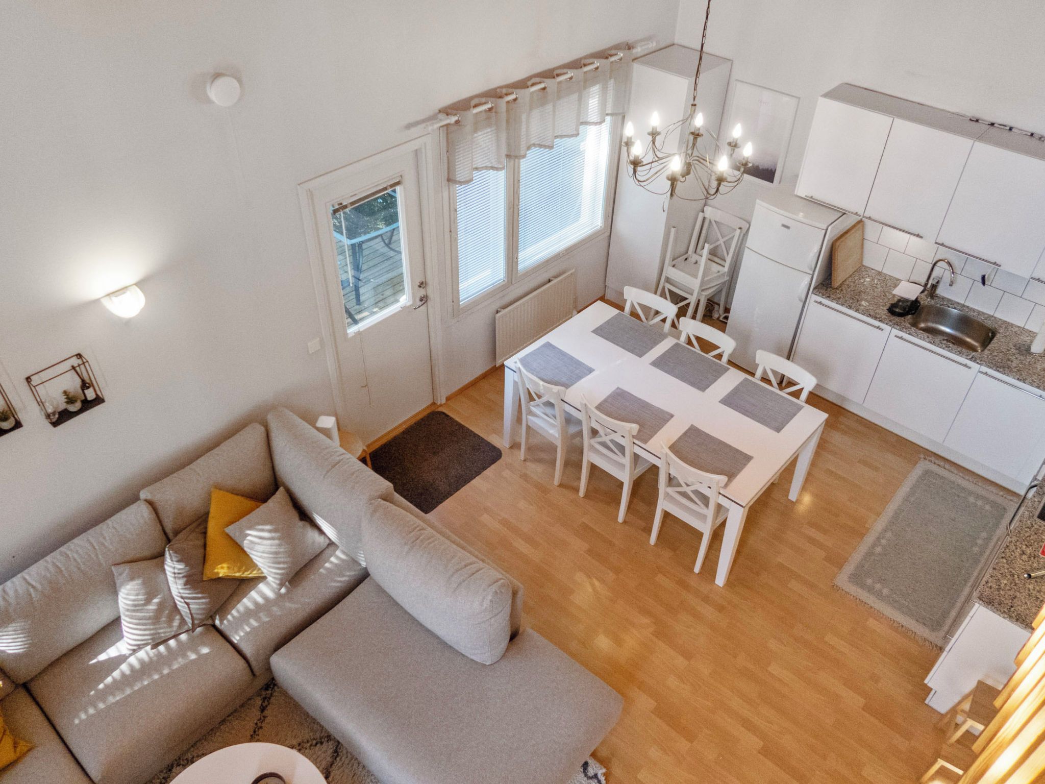 Un espace de vie moderne comprenant un canapé, une table à manger, des chaises, un coin cuisine et un lustre.